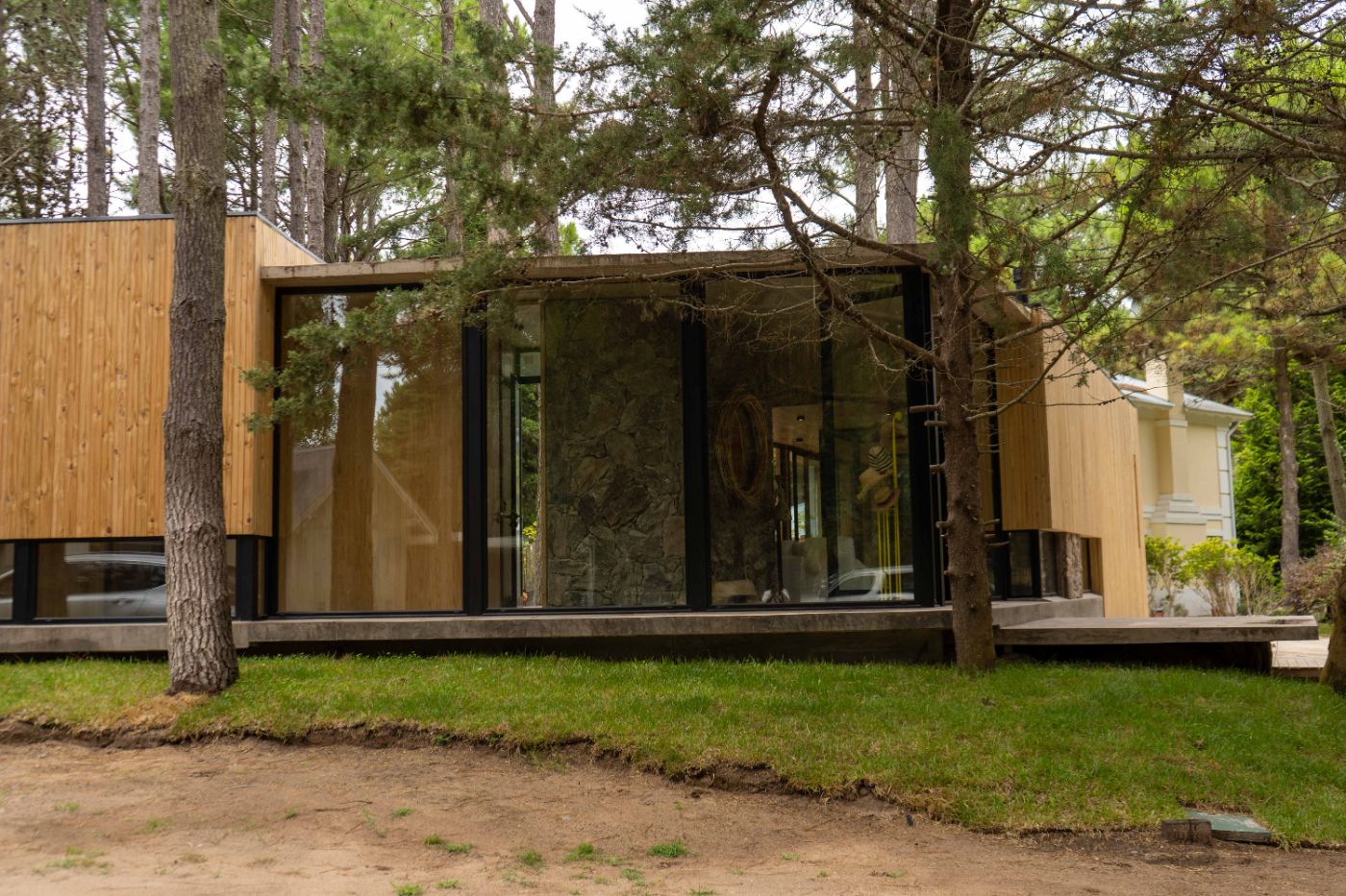 Fachada de vivienda entre pinos con aberturas de aluminio — Villa Gesell